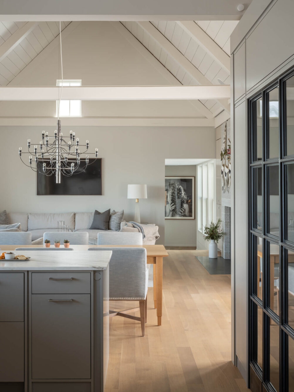 Kitchen with a kitchen island opening into a living room with a table, couch and TV