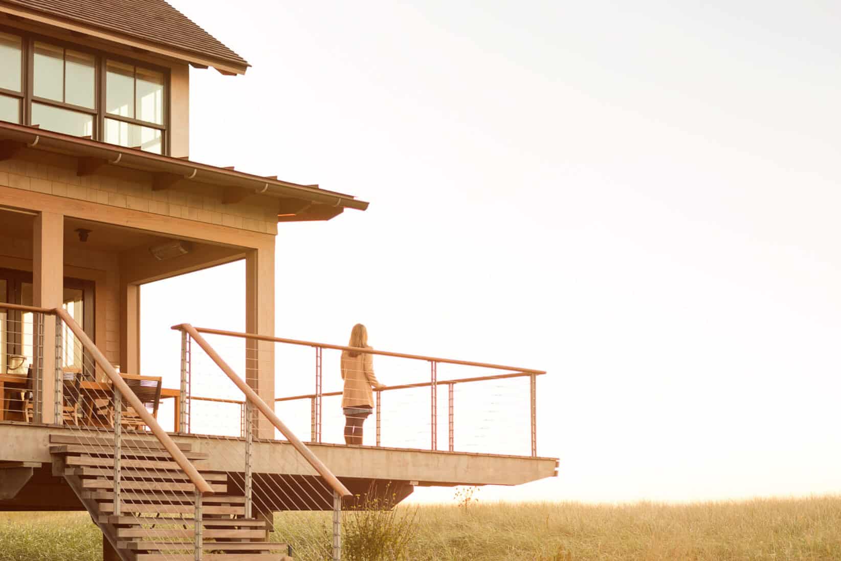 A woman standing on the deck outside at Cast On with the sun rising in the distance