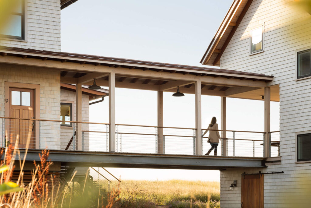 A woman walking along the outdoor covered path between two sections of the house