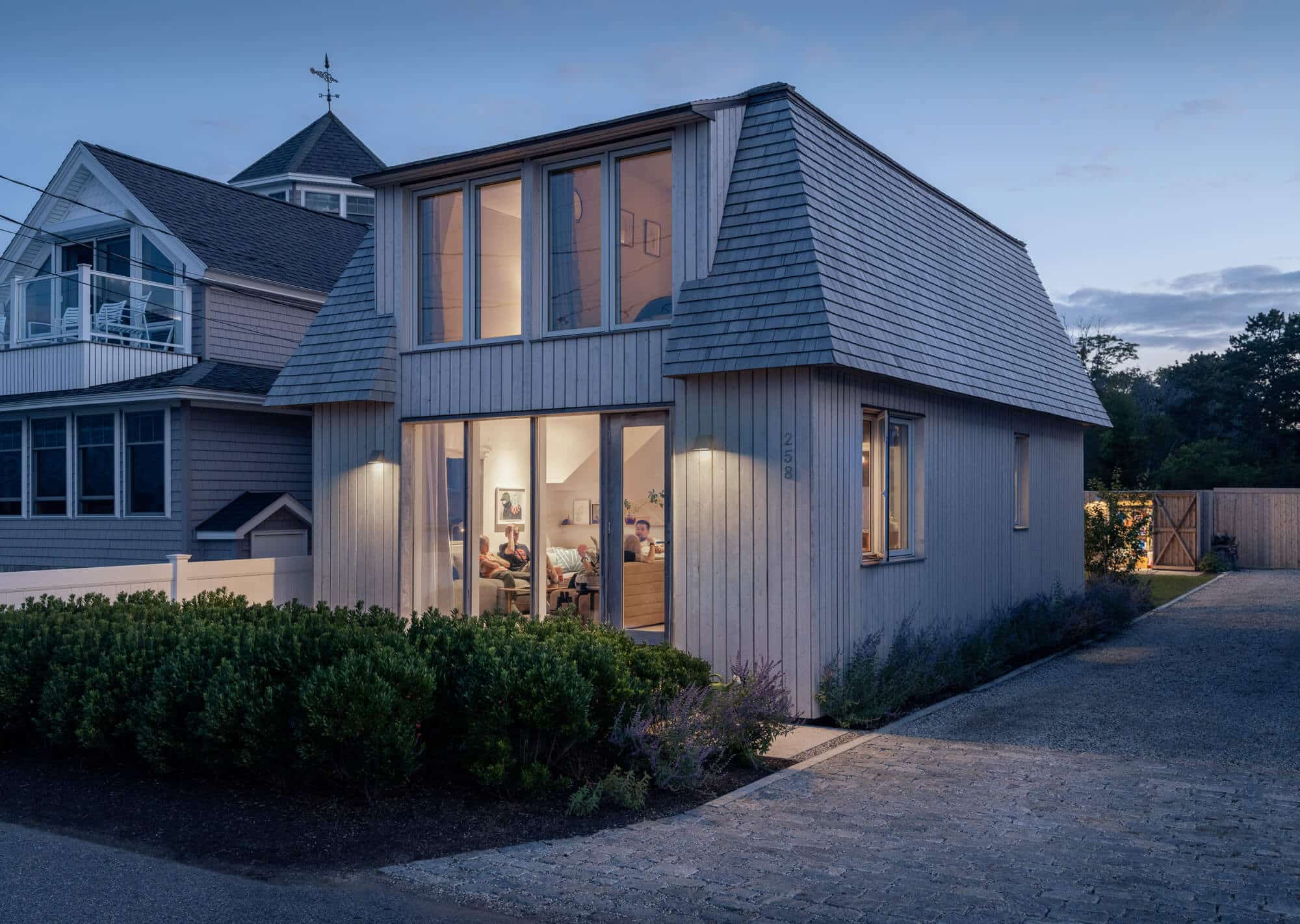 Exterior view of the Hills Beach home at night with a family sitting inside