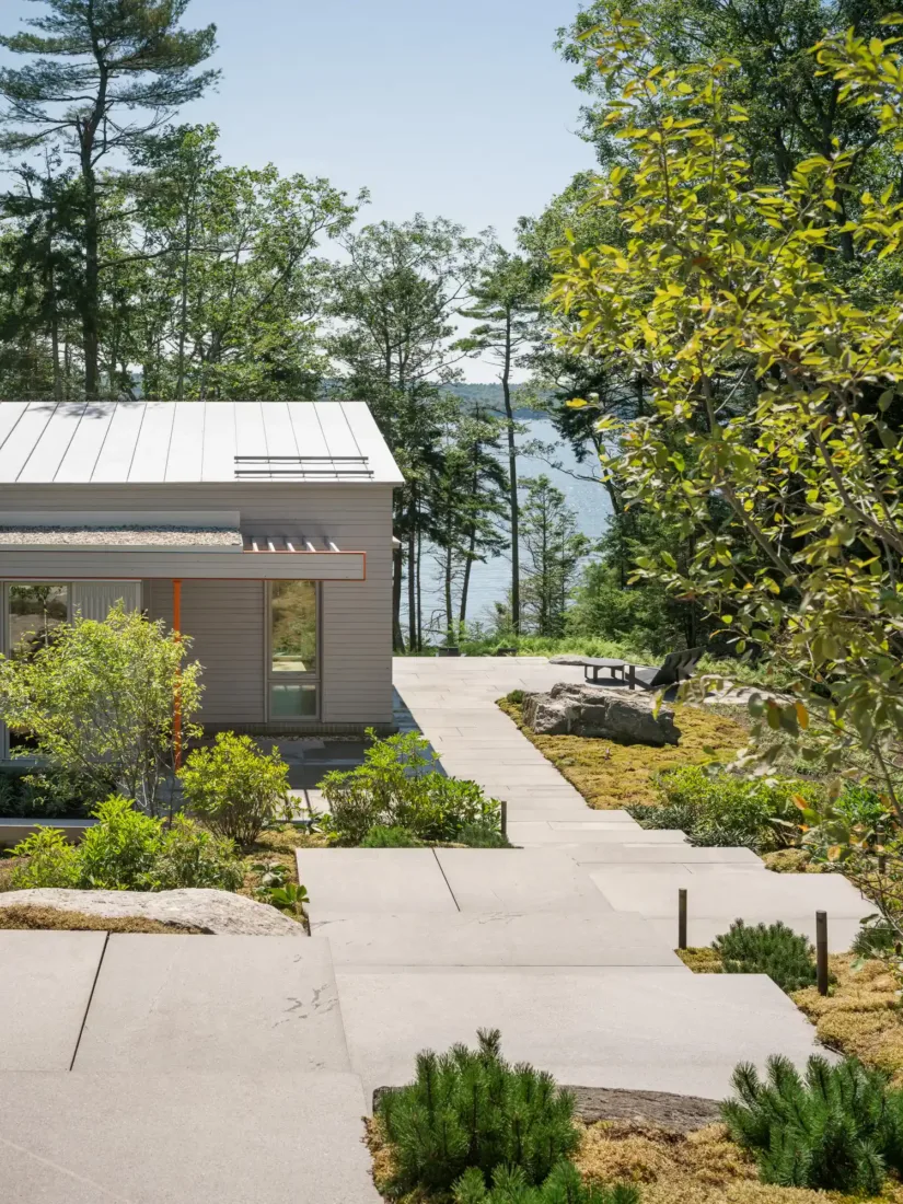 Green Haven’s garden path with modern stone pavers leading toward a serene waterfront view, framed by trees and native plantings
