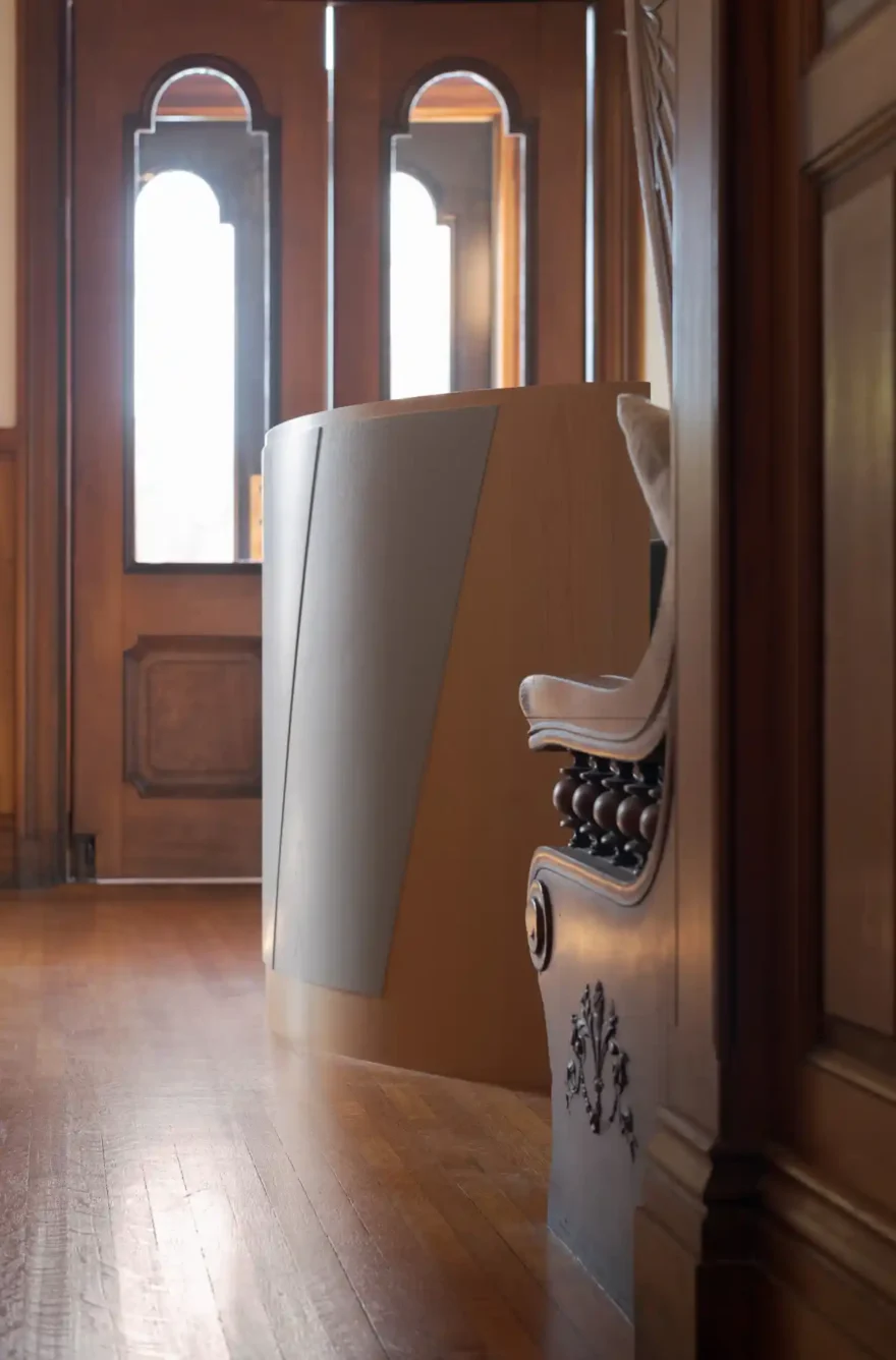 Entryway of the Safford House with historic wood double doors featuring glass inserts, surrounded by rich wood details and natural light streaming in.