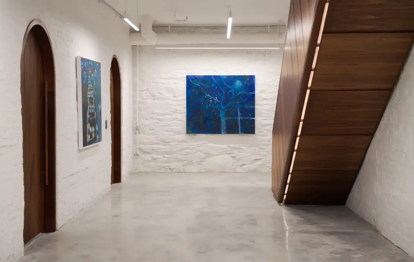 Hallway in the Safford House office with polished stone floors, modern wood staircase, and dark wood doors with oval tops, creating an elegant and welcoming atmosphere.