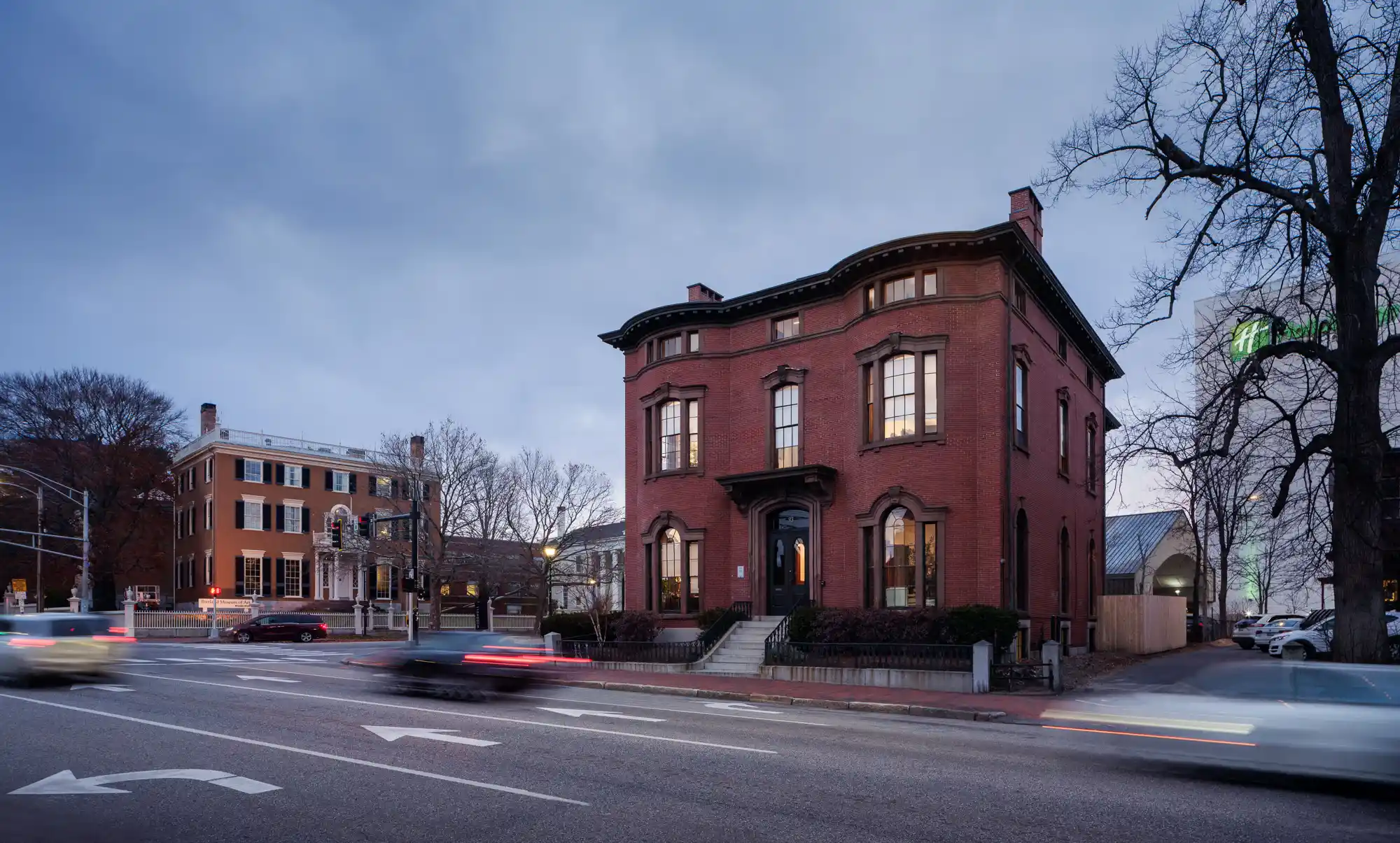 Exterior view of the Safford House at dusk, showcasing the historic brick building with warm lighting highlighting the architectural features.