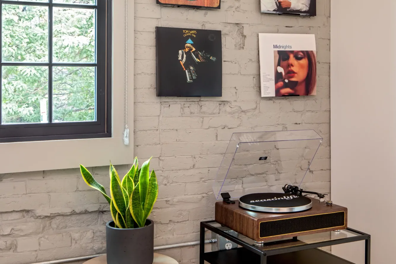 A record player and records posted on a white brick wall at the Weldon Hotel