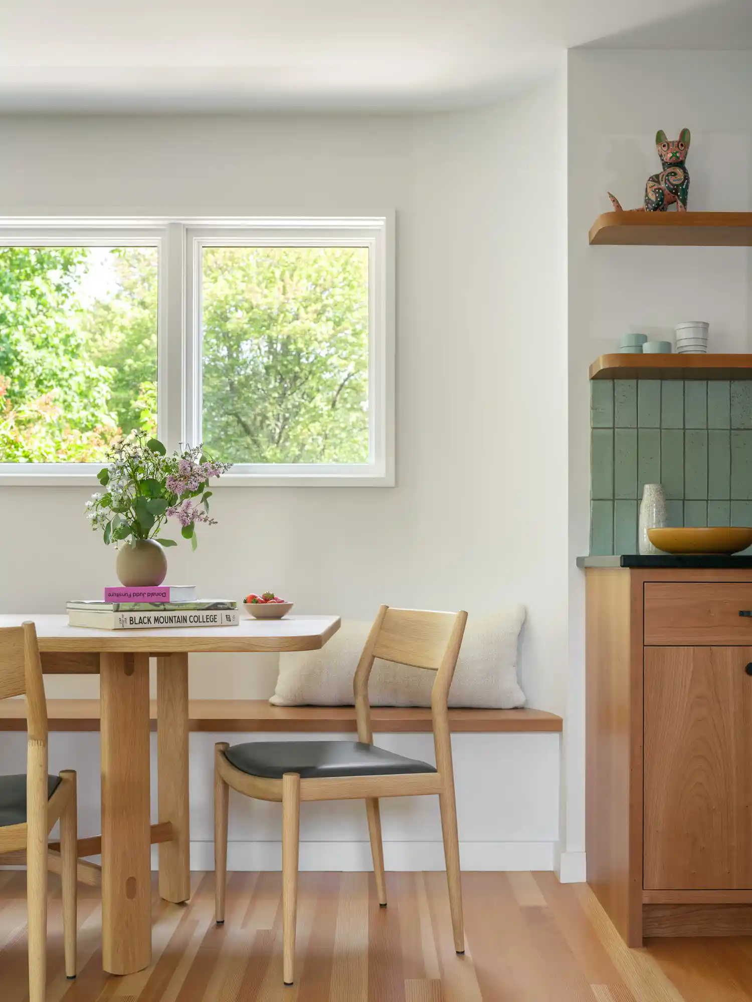 Wood dining table and chairs adjacent to custom kitchen in Willard Cube project