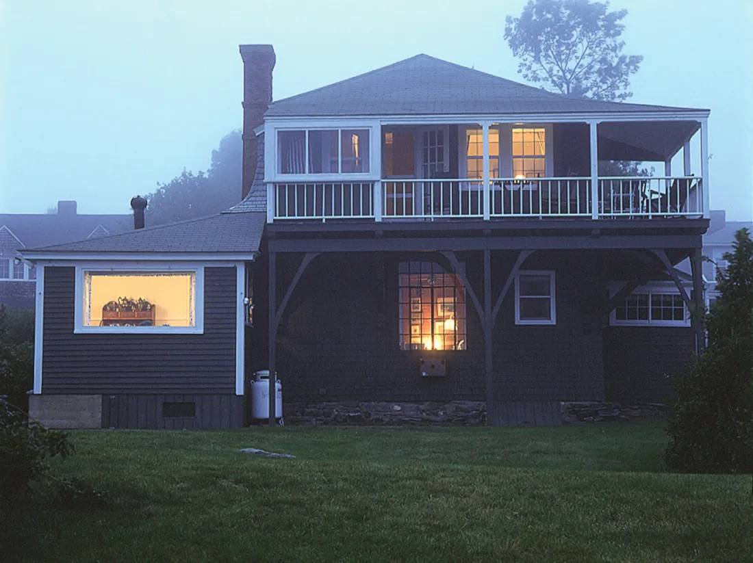 The studio at dusk in fog, with lit windows below the second-story balcony.