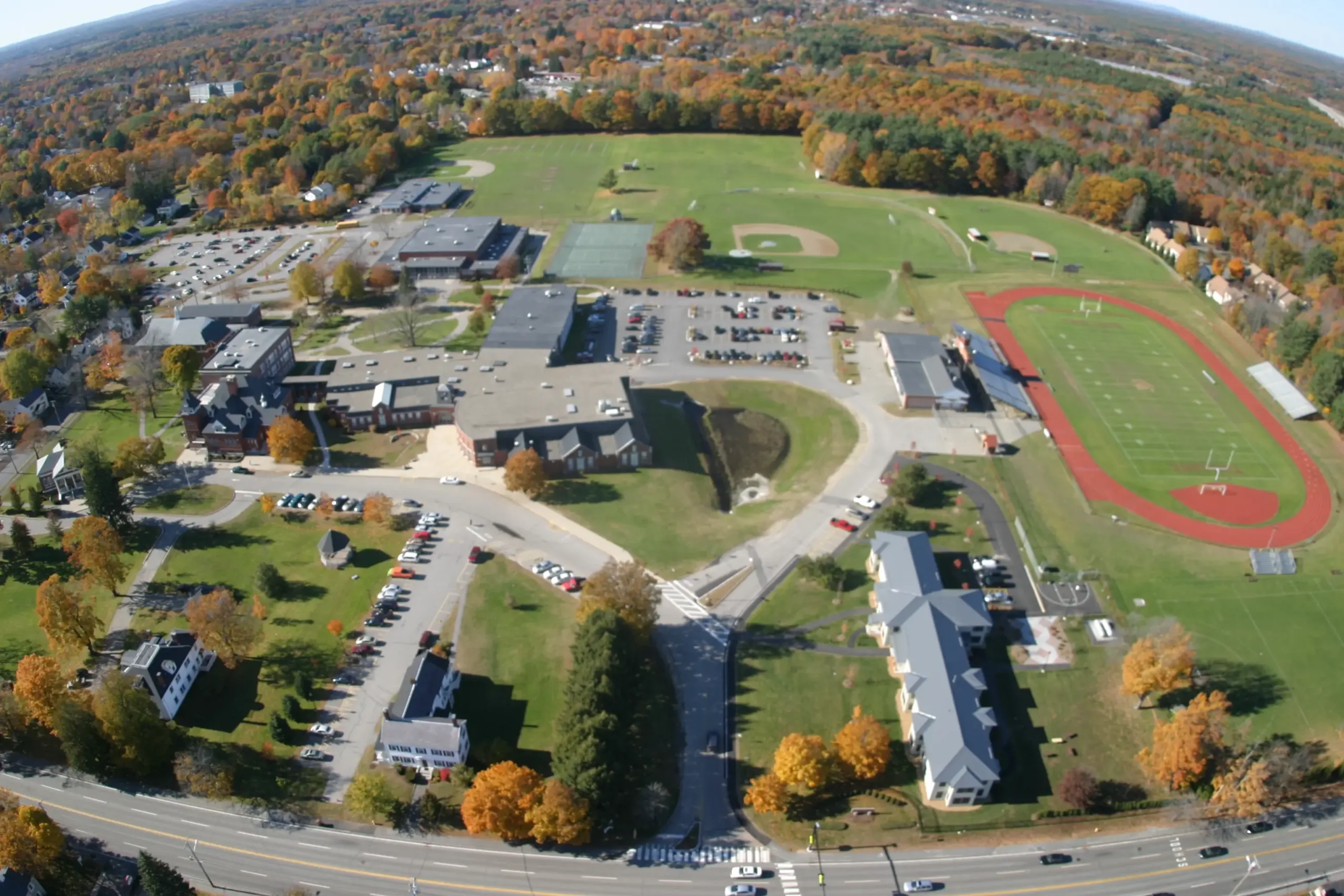 Aerial view of the Thornton Academy campus in Saco with athletic fields, a red running track, and the new dormitory along Main Street.