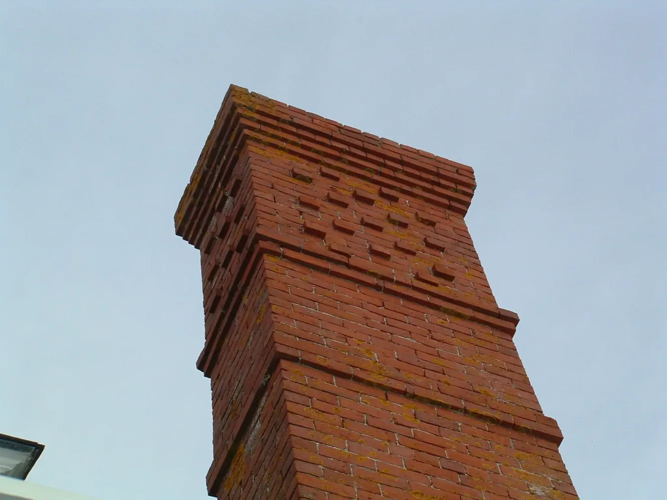 The studio's tall brick chimney seen from below against a pale sky.