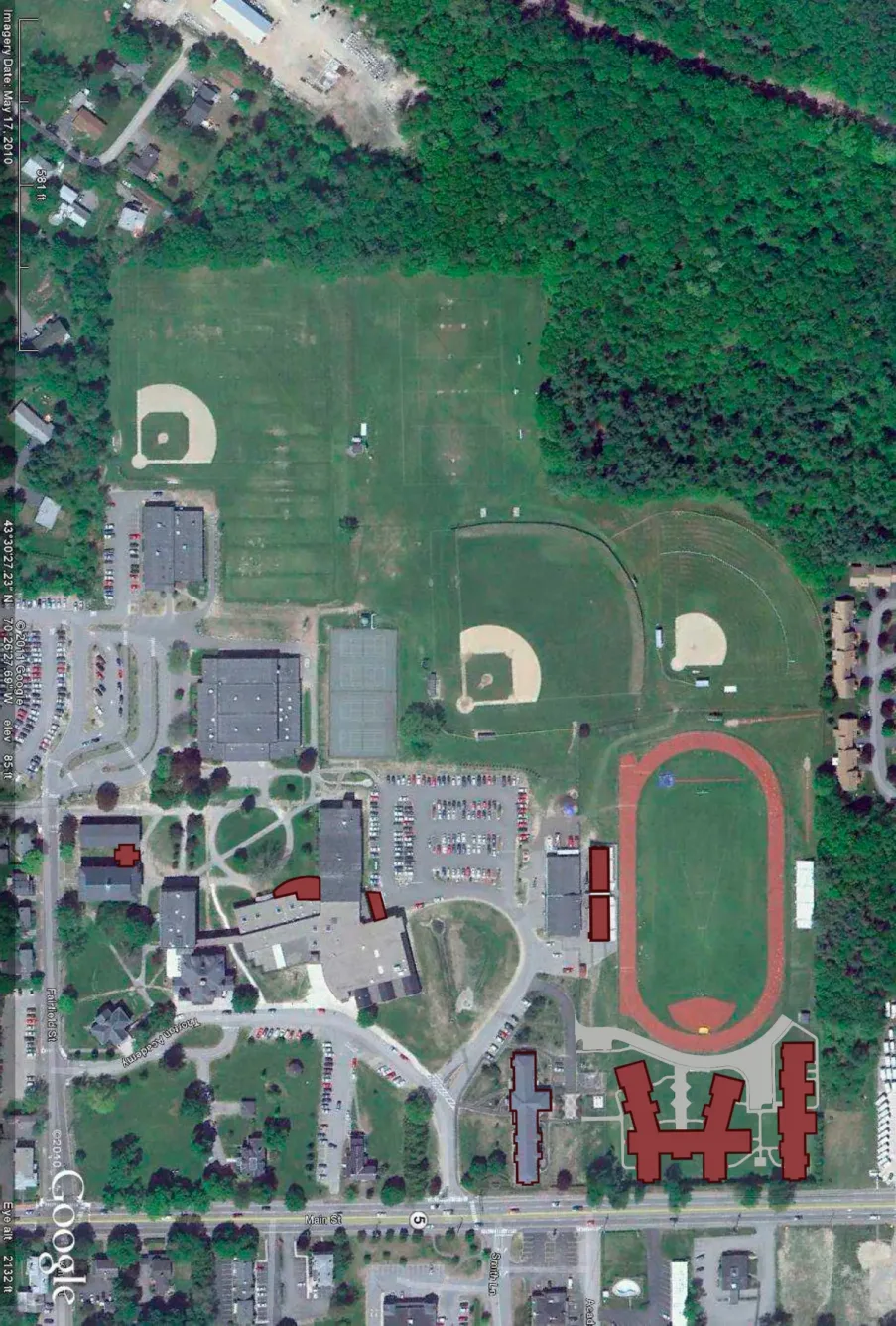 Satellite view of a school campus featuring athletic fields, a running track, several buildings, and a parking lot.