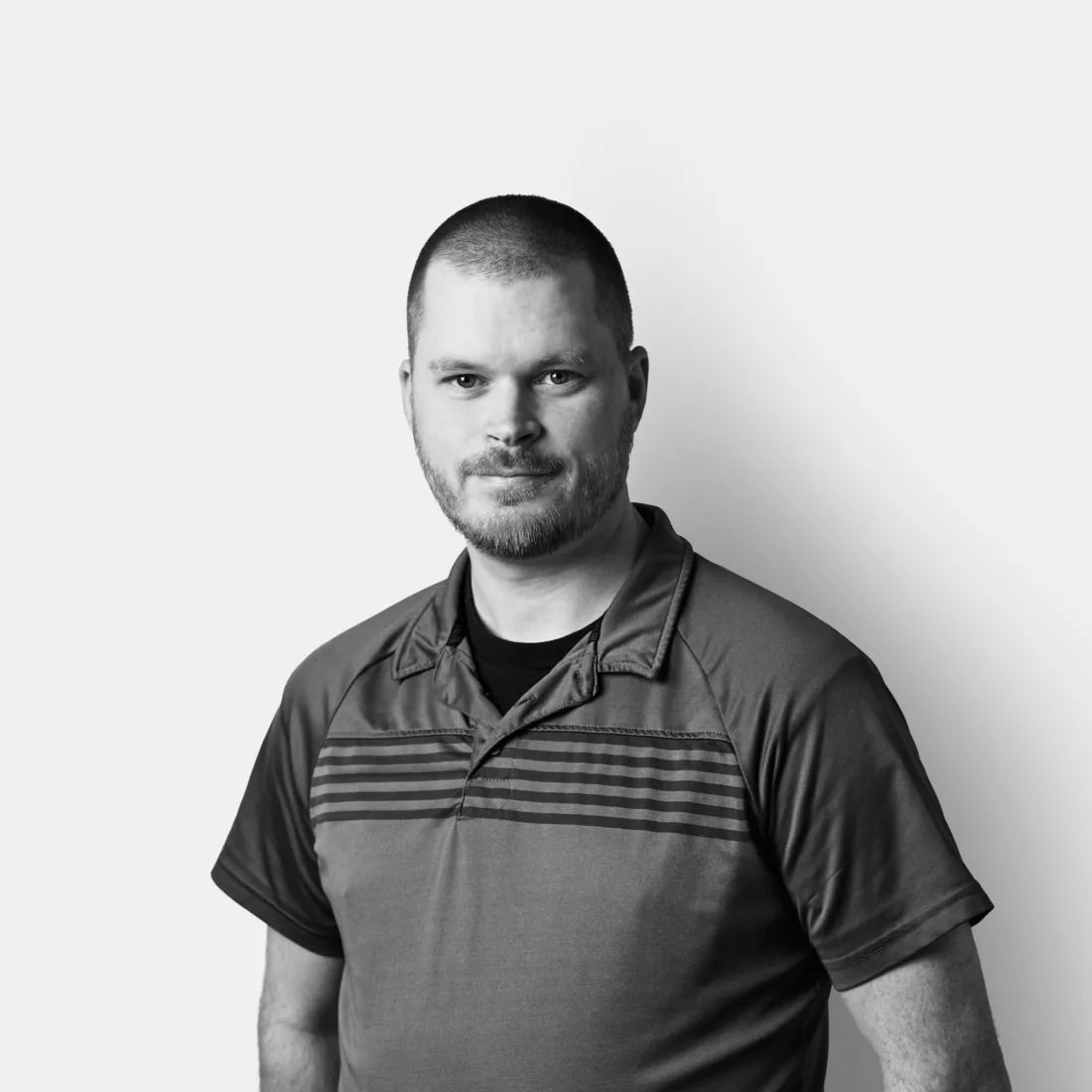 A man with short hair and a beard, wearing a polo shirt, looking at the camera.